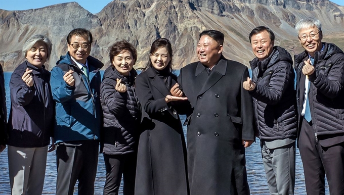 북한 김정은 국무위원장과 리설주 여사가 20일 백두산 천지에서 남쪽 수행원들과 기념사진을 찍고 있다. 처음에는 손을 내리고 있었으나, 강경화 외교부 장관으로부터 "남쪽에서 유행하는 손가락 하트를 해보자"는 제안을 받고 따라하고 있다. 리설주 여사가 김 위원장의 손을 받치고 있다. 청와대 제공