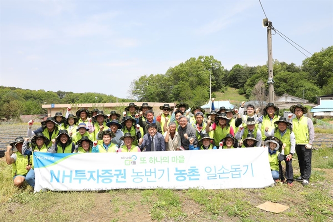 정영채(앞줄 왼쪽 여섯번째) NH투자증권 사장과 임직원, 마을 주민들이 5월 8일 경기 파주 문산읍 당동2리에서 열린 일손돕기 행사 후 기념촬영을 하고 있다. NH투자증권은 전국 29개 농가와 ‘또 하나의 마을’ 결연을 맺고 전 직원이 명예이장, 명예주민으로 활동한다. NH투자증권 제공