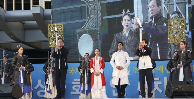 송하진(왼쪽) 전북도지사와 김승환(오른쪽) 전북도교육감이 지난 3일 전북도청 광장에서 열린 제 99회 전국체전과 제38회 전국장애인체전의 성화 안치식에서 이날 강화도 마니산에서 채화해 도착한 성화를 인수받고 있다. 전북도 제공