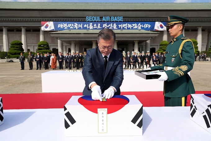 1일 오전 서울공항에서 열린 국군 전사자 유해 봉환식에서 문재인 대통령이 유해 위에 하나씩 6.25전쟁 참전기장을 올려놓고 있다. 청와대사진기자단