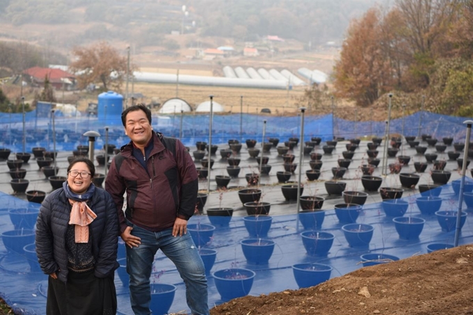 이수진(왼쪽), 김경태씨 부부가 롯데슈퍼 '친환경 청년농부 육성 프로젝트'의 지원을 받아 일군 농장 앞에서 환하게 웃고 있다. 롯데슈퍼 제공