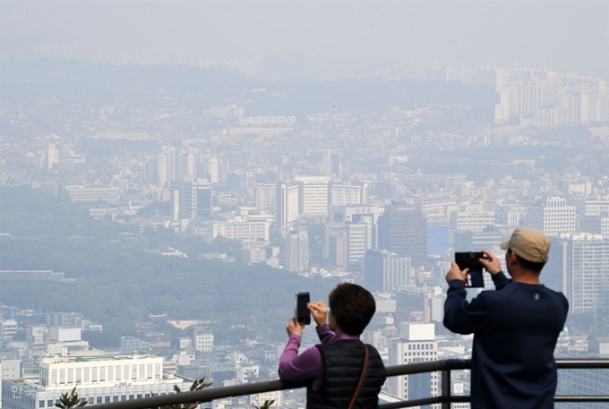 [저작권 한국일보] 서울 시내 미세먼지 스케치 올 가을 처음으로 '나쁨' 수준의 미세먼지 농도가 광범위하게 나타난 15일 오전 서울 남산에서 외국인 관광객들이 서울 도심이 뿌연 가운데 기념촬영을 하고 있다. 홍인기 기자 /2018-10-15(한국일보)