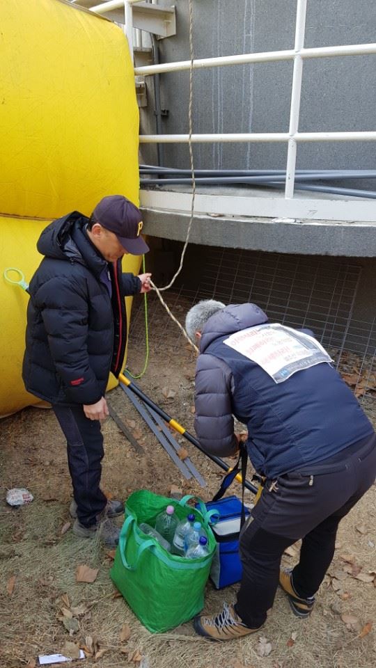 차광호(오른쪽) 파인텍 지회장과 구 스타케미칼 해복투 동료인 정모(왼쪽)씨가 지난 2월 16일 서울 목동 열병합발전소 굴뚝 아래에서 고공농성을 하는 동료들에게 올려 보낼 도시락을 밧줄에 묶고 있다. 신혜정 기자