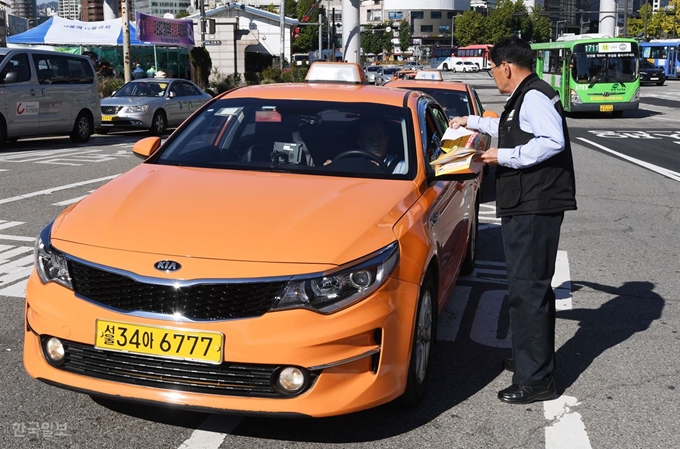 [저작권 한국일보] 서울역 앞 줄 선 택시 카카오가 도입한 카풀 서비스에 반발하는 택시업계 종사자들의 생존권 사수 결의대회를 하루 앞둔 17일 오후 서울역 앞에 승객을 기다리는 택시들이 길게 줄지어 서 있는 가운덴 한 택시운전사가 결의대회 안내 전단을 나눠주고 있다. 홍인기 기자