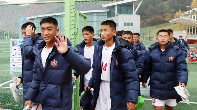 비가 내린 26일 '제5회 아리스포츠컵 국제유소년(U-15) 축구대회'에 참가하기 위해 찾은 북한 4.25 체육단 선수들이 강원 인제군 상남면 체육공원에서 훈련을 마친 뒤 취재진을 향해 손들 들어 인사하고 있다. 연합뉴스