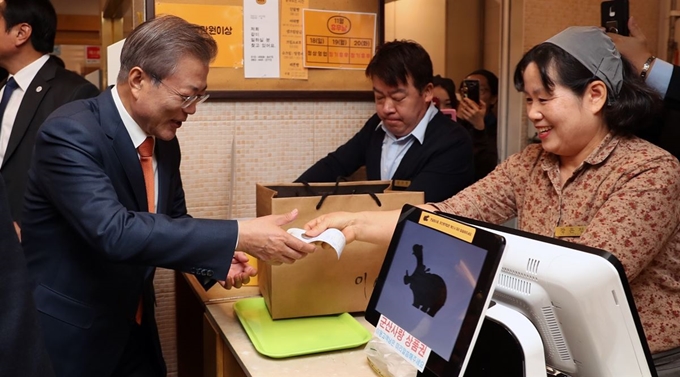 문재인 대통령이 지난달 30일 전북 군산의 이성당을 찾아 군산사랑상품권으로 빵값을 계산한 뒤 영수증을 건네 받고 있다. 연합뉴스