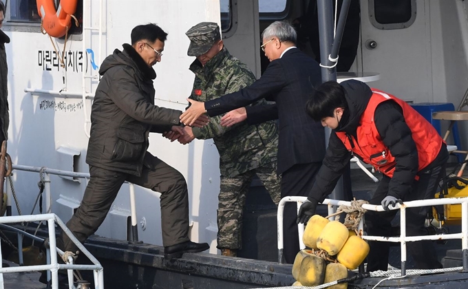 남북 공동 한강하구수로 조사가 시작된 5일 남측 조사 단장인 윤창희(왼쪽 두 번째) 해병대 대령이 선상회의를 하기 위해 강화 교동도 인근 해상에서 북측 선박과 접선해 넘어오는 북측 조사단의 손을 잡아주고 있다. 강화=사진공동취재단