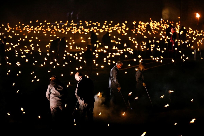 오는 11월 11일 1차 세계대전 종전 100주년을 앞두고 4일(현지시간) 영국 런던탑 해자에서 자원봉사자들이 '짙은 그림자를 넘어서'라는 설치물 일부에 횃불을 밝히고 있다. 로이터 연합뉴스