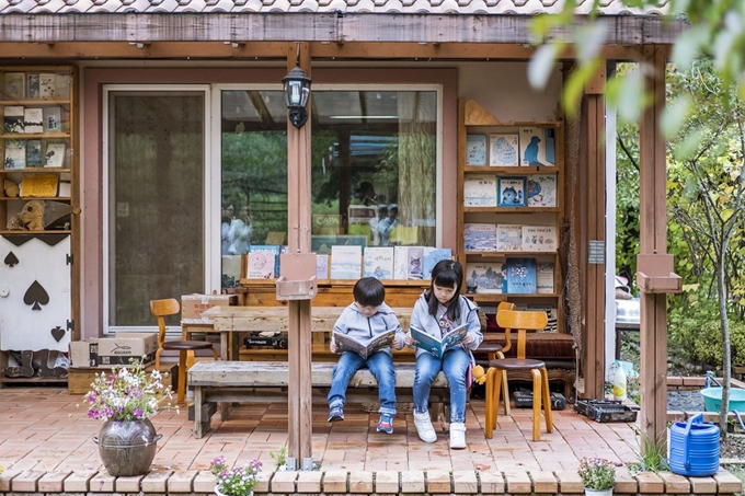 아이들이 괴산 ‘숲속작은책방’ 테라스에서 책을 읽고 있다. 한국관광공사 제공.