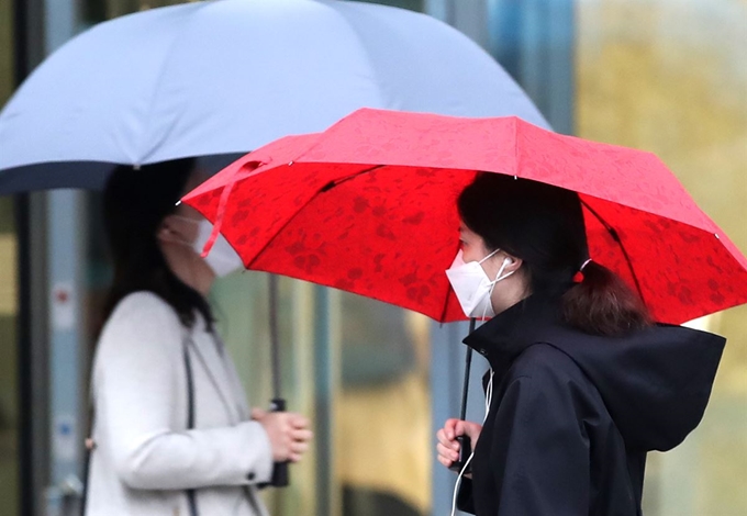 서울을 비롯한 수도권 미세먼지와 초미세먼지 농도가 '나쁨' 수준을 보여 미세먼지 저감조치가 시행된 7일 오전 서울의 한 거리에서 마스크와 우산을 쓴 시민들이 출근길을 서두르고 있다. 연합뉴스