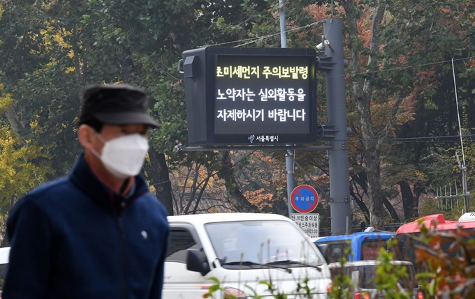 지난 6일 오후 마스크를 쓴 시민이 초미세먼지 주의보 발령을 알리는 서울시청 인근 전광판 앞을 지나가고 있다. 신상순 선임기자