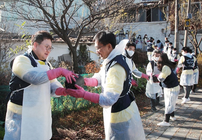 OK저축은행 직원들이 17일 서울 홍제동 개미마을을 찾아 연탄을 나르고 있다. OK저축은행 제공