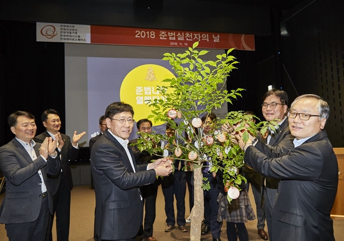 신현우(앞줄 나무 오른쪽) 한화에어로스페이스 대표, 김연철(앞줄 나무 왼쪽) 한화정밀기계ㆍ한화테크윈 대표 등 한화그룹 임직원들이 19일 서울 중구 한화빌딩에서 가진 ‘2018 준법실천자의 날’ 행사에서 준법나무에 격려문구를 적은 메모를 달고 있다. 한화 제공