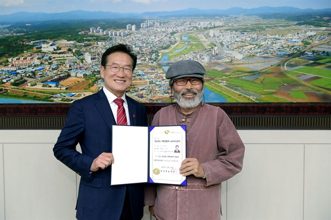 조병현 목조각장이 21일 최기문 시장에게 무형문화재 제 45호 지정 인정서를 전달받았다. 영천시 제공