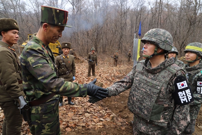 남북군사당국이 '판문점선언 이행을 위한 군사분야 합의서'에 따라 공동유해발굴의 원활한 추진을 위해 강원도 철원 '화살머리고지' 일대에서 남북 도로개설을 추진하고 있는 가운데, 22일 도로연결 작업에 참여한 남북인원들이 군사분계선(MDL) 인근에서 인사하고 있다. 국방부 제공