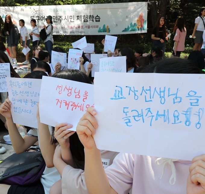 서울 동구여중 학생들이 지난 8월 22일 종로구 서울시교육청 인근 경희궁 앞마당에서 학교 정상화를 촉구하는 글귀를 담은 손팻말을 들고 시위하고 있다. 연합뉴스