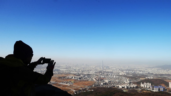 미세먼지 농도가 '나쁨' 수준을 보인 28일 오전 경기도 광주시 남한산성에서 시민들이 파란 하늘 아래 미세먼지 덮인 서울 시내를 휴대전화기로 촬영 하고 있다. 연합뉴스