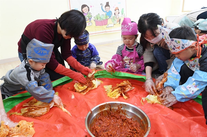 21일 부산 동래구 부산경찰청 어린이집에서 원생들이 할아버지, 할머니와 함께 김장 매트 위에서 김장을 담그고 있다. 김장 매트가 등장한 건 2014년 경으로 추정된다. 한국일보 자료사진