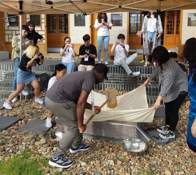 지난 8월 롯데면세점의 ‘글로벌 앰배서더’ 한국문화탐방 프로그램에 참가한 외국인 유학생들이 충남 공주한옥마을에서 인절미 떡메치기 체험을 하고 있다. 롯데면세점 제공