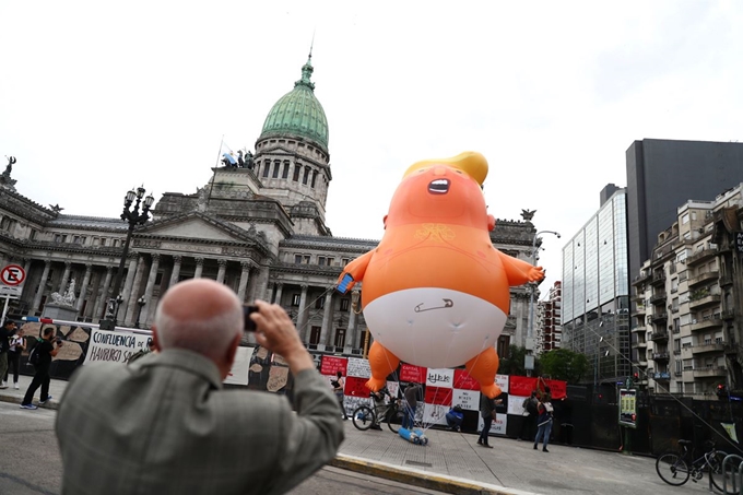 G20 정상회의 개막을 앞두고 29일(현지시간) 한 시민이 아르헨티나 부에노스아이레스의 의회 앞에 G20 반대 시민단체가 세운 트럼프 대통령을 풍자한 '베이비 트럼프' 를 촬영하고 있다. 로이터 연합뉴스