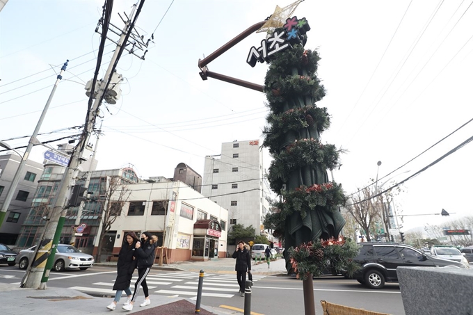 서울 서초구가 4일부터 횡단보도와 교통섬 등에 설치한 대형 그늘막'서리풀원두막'을 '서리풀 트리'로 바꿔 운영한다. 트리는 그늘막을 접어 보호 커버를 씌우고 소형 전구와 솔방울, 꽃잎 등을 달아 꾸몄다. 사진은 이날 강남대로의 한 횡단보도에 설치된 '서리풀 트리'. 연합뉴스