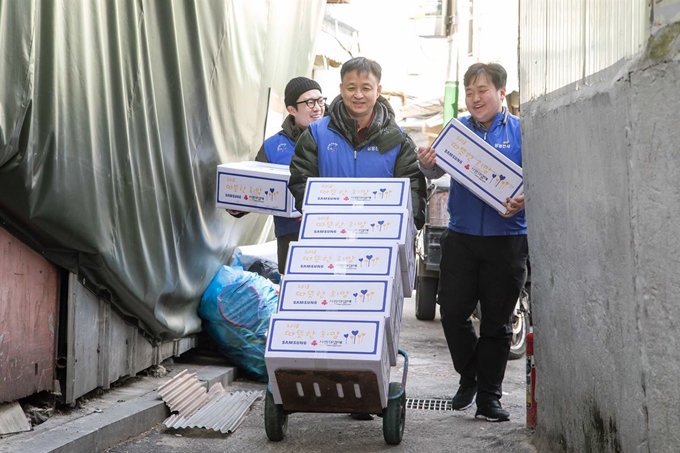 삼성전자 임직원들이 서울의 한 쪽방 밀집지역에 전달할 생필품 상자를 나르고 있다. 삼성전자 제공