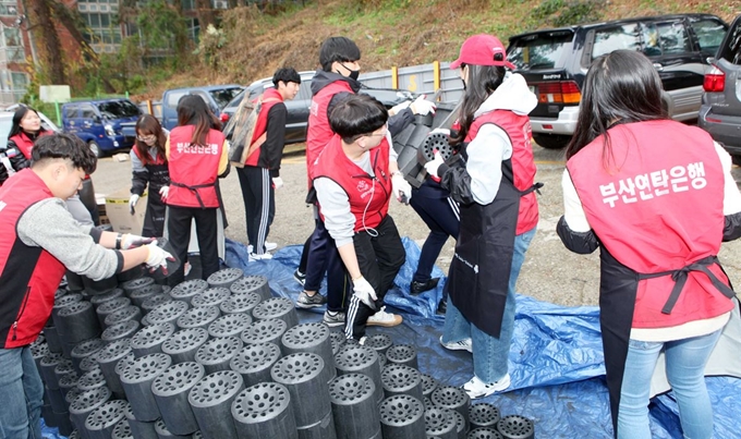 6일 부산 금정구의 한 중학교 인근에서 부산외국어대학교 BUFS글로벌봉사단 소속 학생과 교직원 등 50여 명이 어려운 이웃에게 전달할 연탄을 옮기고 있다.이 대학 봉사단은 이날 연탄 2000장을 소외계층 가정에 배달했다. 뉴시스