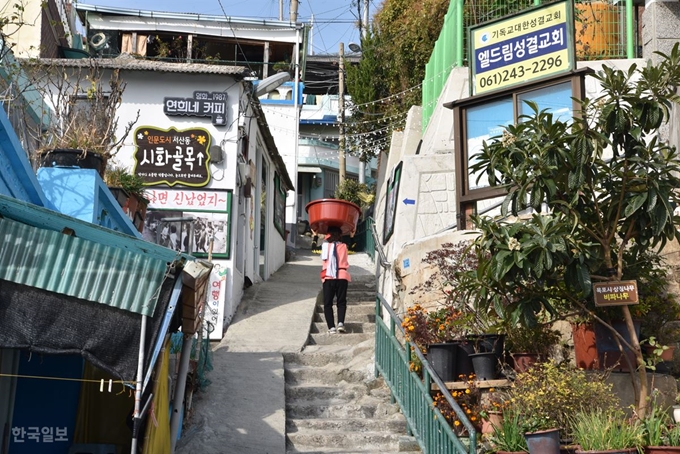 한 주민이 몸집보다 큰 고무대야를 이고 골목을 오르고 있다.