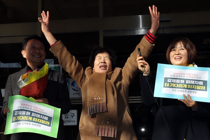 일본 미쓰비시중공업을 상대로 3차 손해배상 청구 소송을 제기한 일제 강제노역 피해자의 유족 이경자 씨(가운데)가 14일 오후 광주 동구 지산동 광주지방법원 청사 앞에서 만세를 외치고 있다. 3차 소송 항소심 재판부는 1심에 이어 이날 미쓰비시의 배상 책임을 인정했다. 연합뉴스