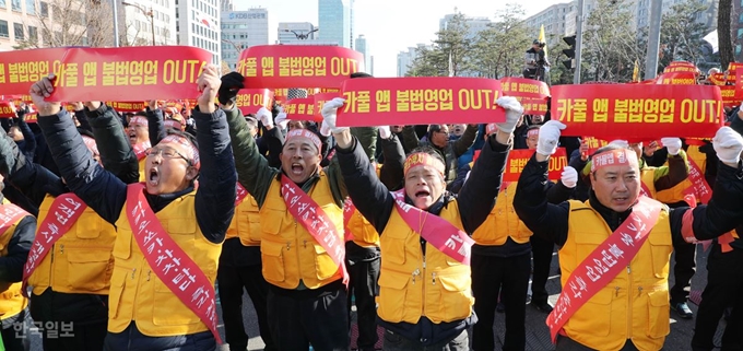 전국택시노동조합연맹과 전국민주택시노동조합연맹, 전국개인택시운송사업조합연합회, 전국택시운송사업조합연합회 등 택시 4단체 종사자들이 지난달 22일 오후 서울 여의도 국회 앞에서 열린 제2차 택시 생존권 사수 결의대회에서 '카풀 앱 불법영업 OUT'이 적힌 손팻말을 흔들며 구호를 외치고 있다. 이들은 결의대회를 통해 카풀 영업행위 강력 규탄과 함께 국회를 향해 상업적 카풀앱을 금지하는 법개정을 촉구했다. 배우한 기자