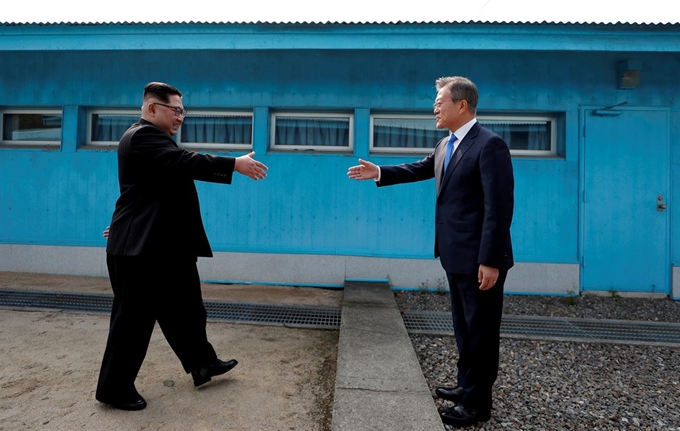 4월 27일 문재인 대통령과 김정은 북한 국방위원장이 판문점에서 군사분계선을 가운데 두고 악수를 하려고 하는 모습. 한국사진기자 풀 제공