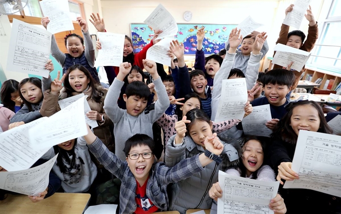 21일 오전 서울 강남구 삼성로 언북초등학교에서 겨울방학식을 마친 3학년 학생들이 겨울 방학생활 안내문을 들고 기뻐하고 있다. 뉴스1