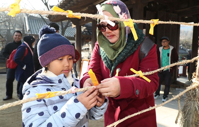 22일 동지를 맞아 열린 서울 남산골한옥마을 세시절기행사 '동지첨치'에 참가한 외국인 관광객 가족이 소원을 적어 달고 있다. 연합뉴스