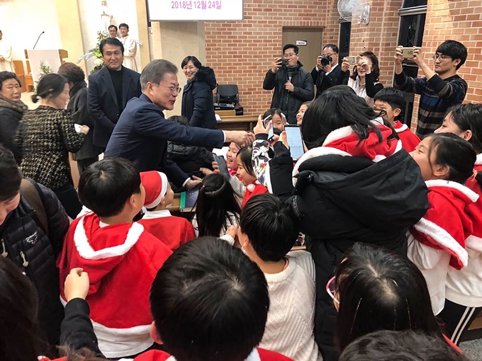 문재인 대통령이 24일 오후 경남 양산시 덕계 성당에서 열린 성탄 전야 미사에 참석해 어린이들과 인사하고 있다. 청와대 제공