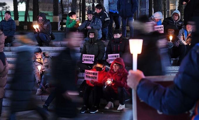 지난 24일 청계광장에서 택배기사와 시민들이 CJ대한통운이 대회에 나설 것을 촉구하는 촛불을 밝히고 있다.