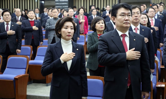 나경원(왼쪽) 원내대표를 비롯한 자유한국당 의원들이 26일 국회에서 열린 의원총회에서 국기에 경례하고 있다. 연합뉴스