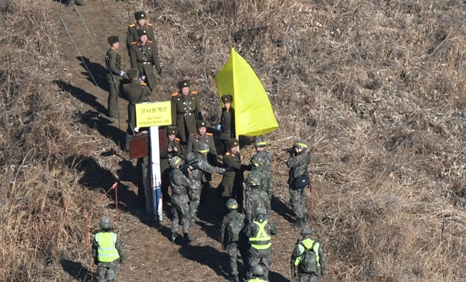 남북이 ‘9ㆍ19 군사분야 합의서’ 이행 차원에서 최근 시범 철수한 비무장지대(DMZ) 내 감시초소(GP)들을 상호 방문 검증하기로 약속한 지난달 12일 남북 현장검증반이 황색 깃발로 표시된 강원 철원군 중부전선 군사분계선(MDL)에서 만나 인사를 나누고 있다. 철원=사진공동취재단