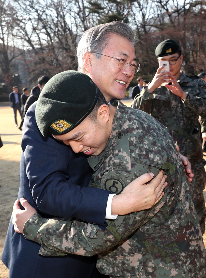 문재인 대통령이 지난 19일 오후 청와대 녹지원에서 남북 공동 유해발굴지역 지뢰 제거 및 도로 개설 작전을 수행한 화살머리고지 장병들을 격려하며 포옹하고 있다. 청와대 제공