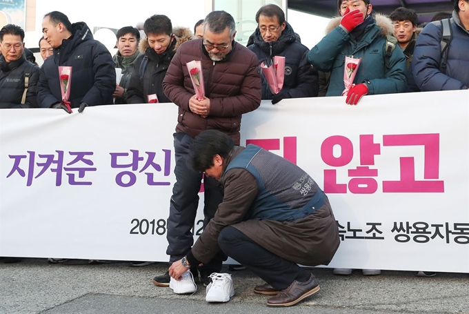 일 오전 경기 평택시 쌍용자동차 평택공장 앞에서 열린 쌍용차 해고 노동자 복직 첫 출근 기념행사에서 김득중 금속노조 쌍용차지부장(오른쪽)이 김정우 전 지부장에게 새 신발을 선물하고 있다. 연합뉴스