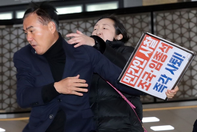 31일 오전 서울 영등포구 여의도 국회에서 열린 국회 운영위원회에 참석하기 위해 조국 민정수석과 임종석 비서실장이 국회 본청에 도착하자 인지연 대한애국당 대변인이 '민간인 사찰 조국 임종석 즉각 사퇴!'가 적힌 피켓을 들고 소리를 지르자 국회 관계자가 피켓을 빼앗고 있다. 뉴시스