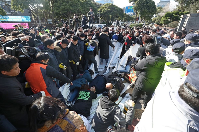 제주시청 직원들이 7일 오후 제주도청 앞에 설치된 제2공항 반대 농성 천막을 철거하자 농성자들이 천막 천을 붙잡고 저항하고 있다. 연합뉴스.