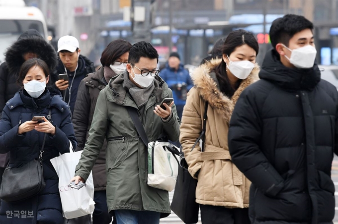 고농도 미세먼지로 수도권을 포함한 전국 곳곳에 미세먼지 비상저감조치가 시행된 14일 오전 서울 광화문사거리에서 줄근길 시민들이 마스크를 쓴 채 횡단보도를 건너고 있다. 홍인기 기자