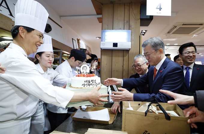 문재인 대통령이 24일 오후 전국경제투어로 대전을 방문, 대전의 명물 성심당 빵집에서 튀김 소보로를 구매한 후 직원들로부터 깜짝 생일 축하 케이크를 받고 있다. 연합뉴스