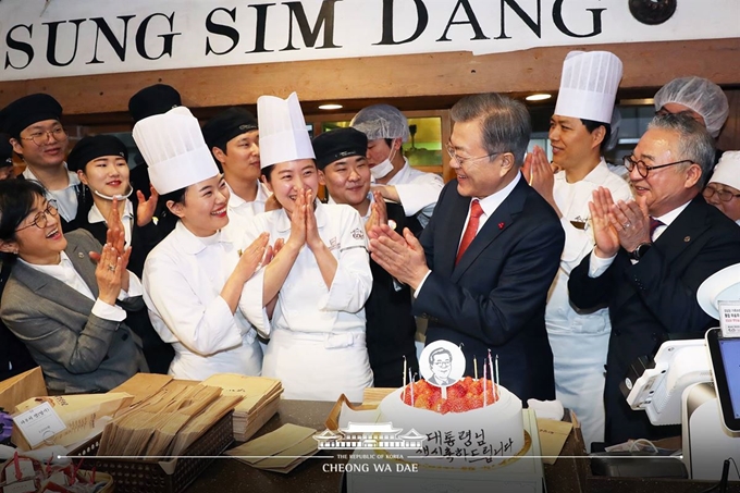 문재인 대통령이 24일 오후 전국경제투어로 대전을 방문, 대전의 명물 성심당 빵집에서 튀김 소보로를 구매한 후 직원들로부터 깜짝 생일 축하 케이크를 받고 있다. 청와대 페이스북.