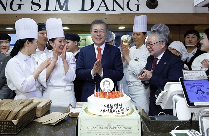 문재인 대통령이 24일 오후 전국경제투어로 대전을 방문, 대전의 명물 성심당 빵집에서 튀김 소보로를 구매한 후 직원들로부터 깜짝 생일 축하 케이크를 받고 있다. 연합뉴스