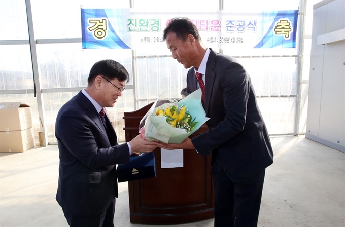 이종원(왼쪽) 청주자원화㈜대표가 25일 청주 친환경에너지타운 준공식에서 김병학 주민협의체 대표로부터 감사패와 꽃다발을 받고 있다. 청주시 제공