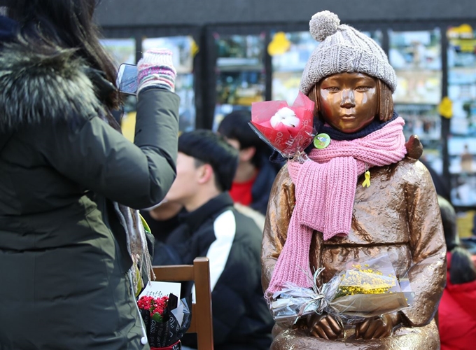 2일 서울 종로구 옛 일본대사관 앞에서 열린 새해 첫 일본군 성노예 문제해결을 위한 수요집회에서 한 시민이 평화의 소녀상에게 솜꽃을 달아준 뒤 촬영하고 있다. 연합뉴스