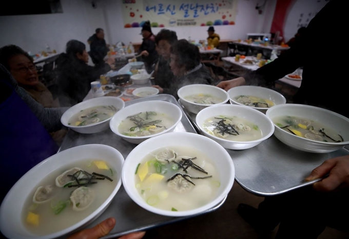 설 명절을 앞두고 29일 서울 관악구 낙성대동 주민센터에서 열린 어르신 설날잔치에서 중앙사회복지관 관계자들이 이 지역에 거주하는 어르신들에게 떡만둣국을 대접하고 있다. 연합뉴스