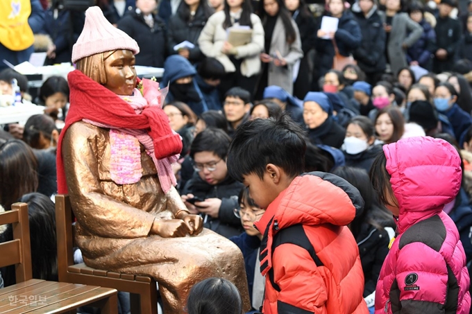 [저작권 한국일보]30일 열린 정기수요집회에서 아이들이 소녀상을 바라보고 있다. 이한호 기자