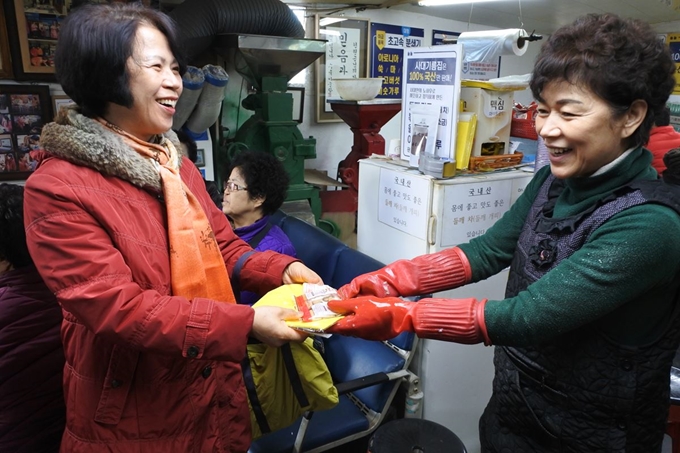 삼대기름집 안주인 전유산씨가 손님에게 건빵과 요구르트를 건네고 있다. 이준호 기자